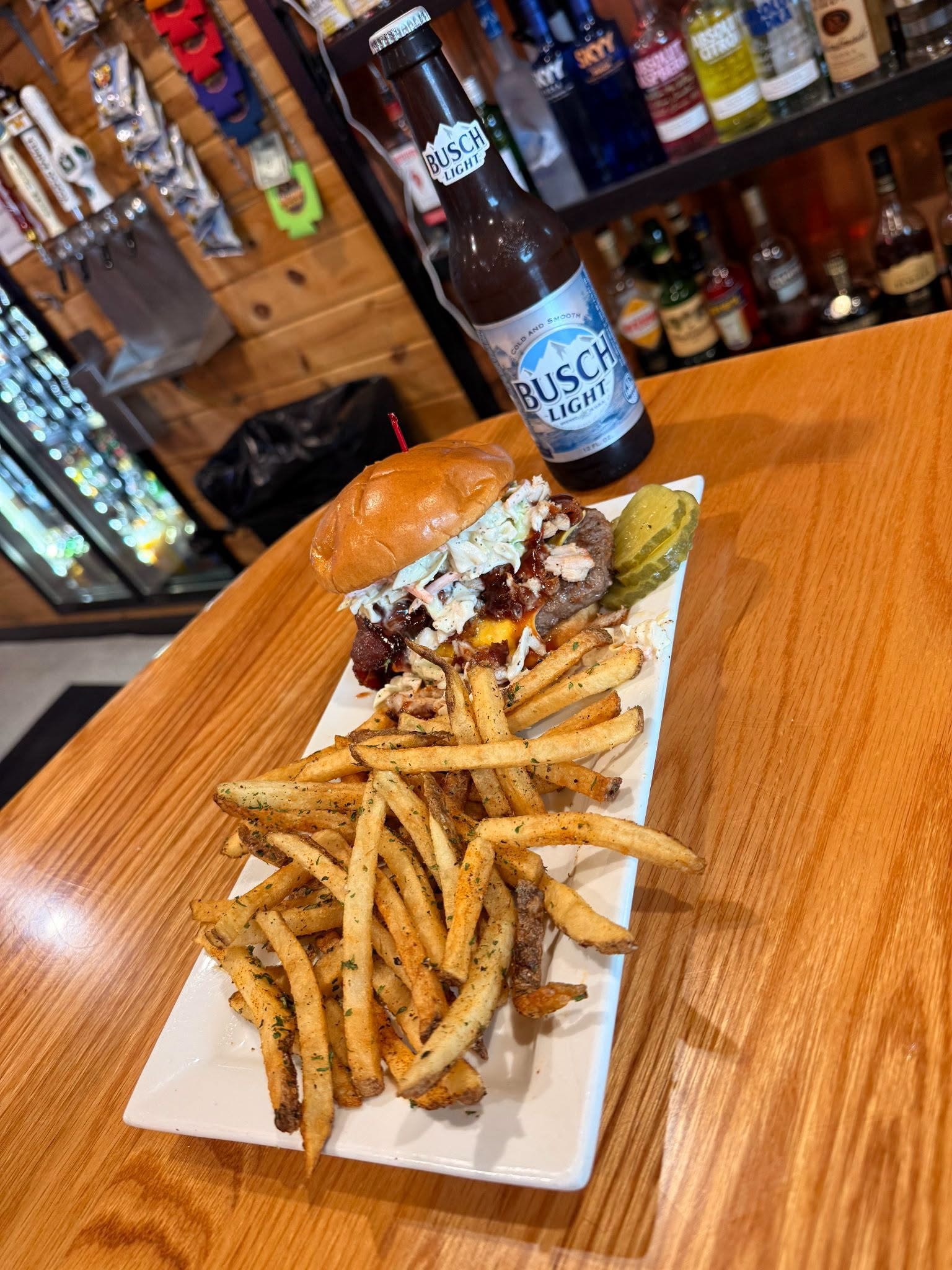BBQ burger with coleslaw, bacon, and house-cut fries with a Busch Light
