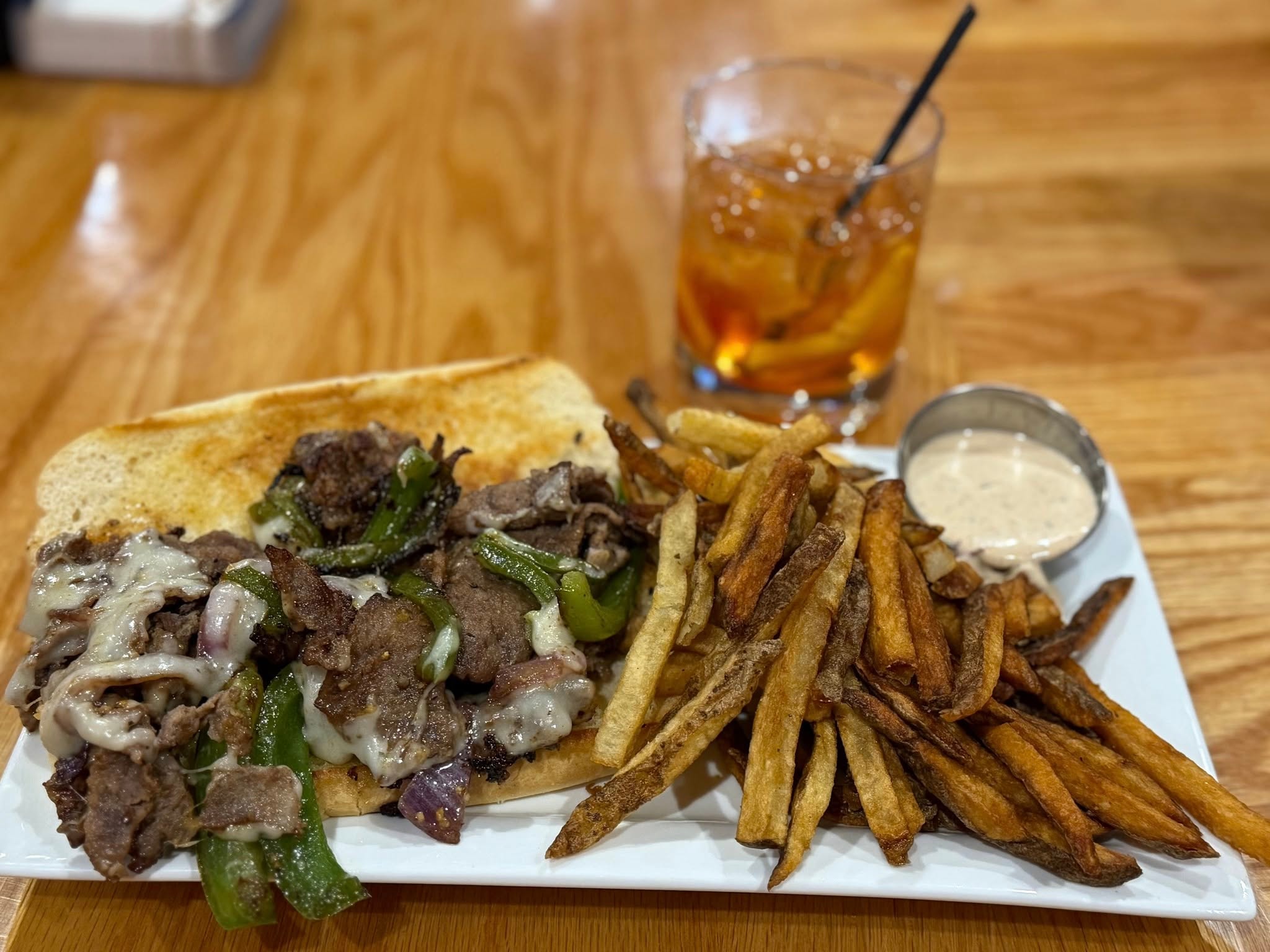Philly cheesesteak sandwich with peppers, onions, provolone, and house-cut fries