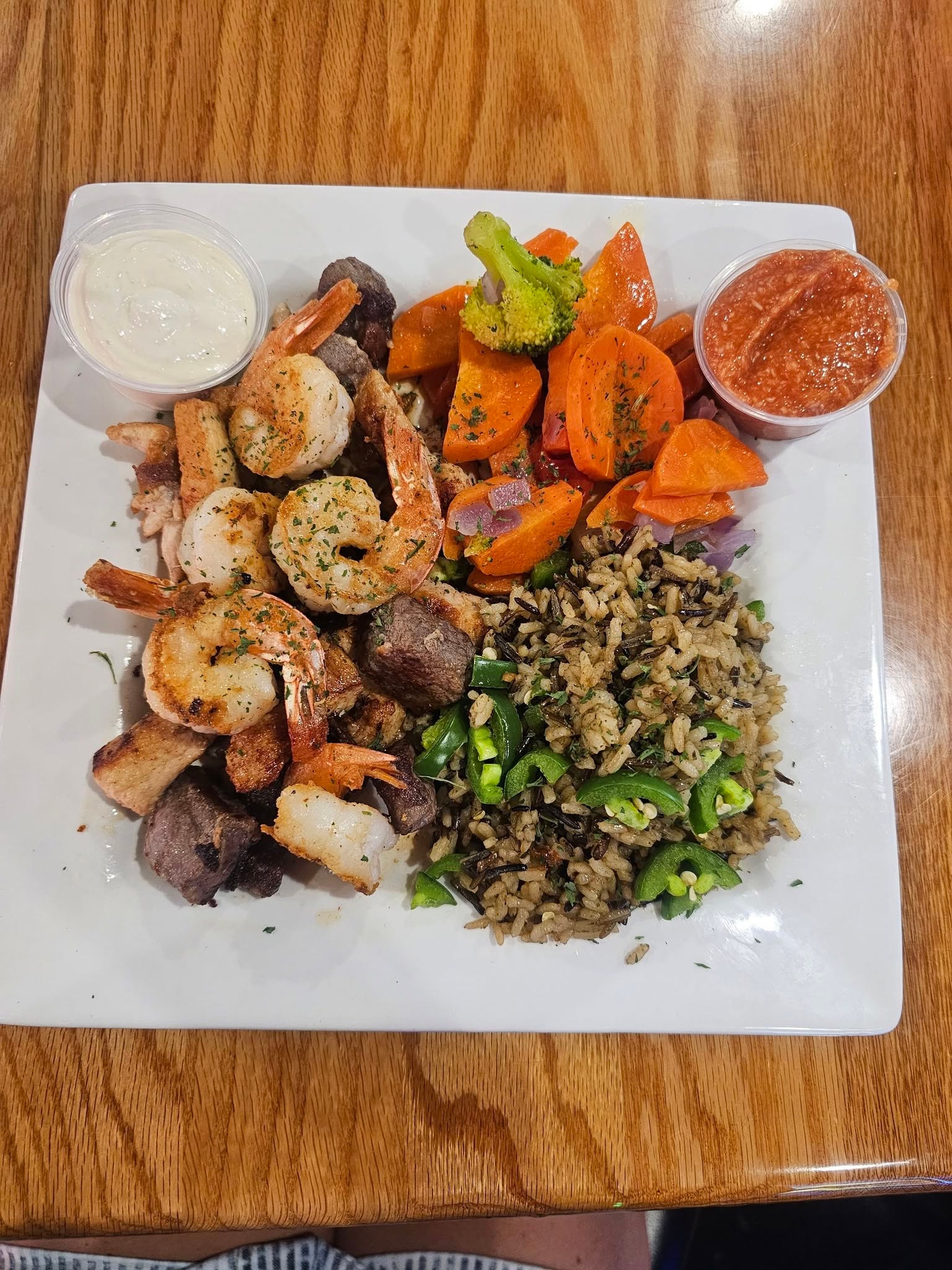 Grilled shrimp and steak skewer with wild rice, roasted vegetables, and dipping sauces