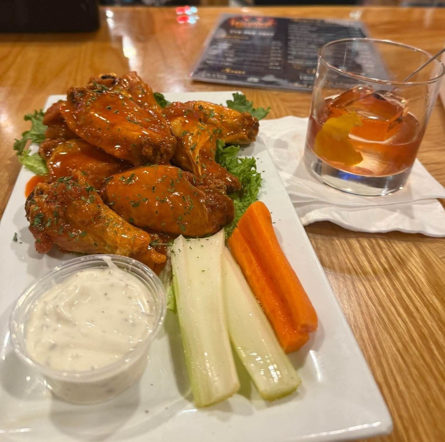 Buffalo wings with ranch, celery, carrots, and an old fashioned cocktail